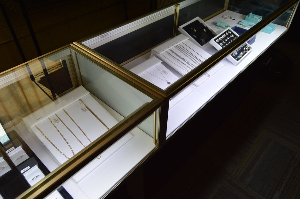 Long glass jewelry counters showcasing gold chains, bracelets, and estate designer pieces