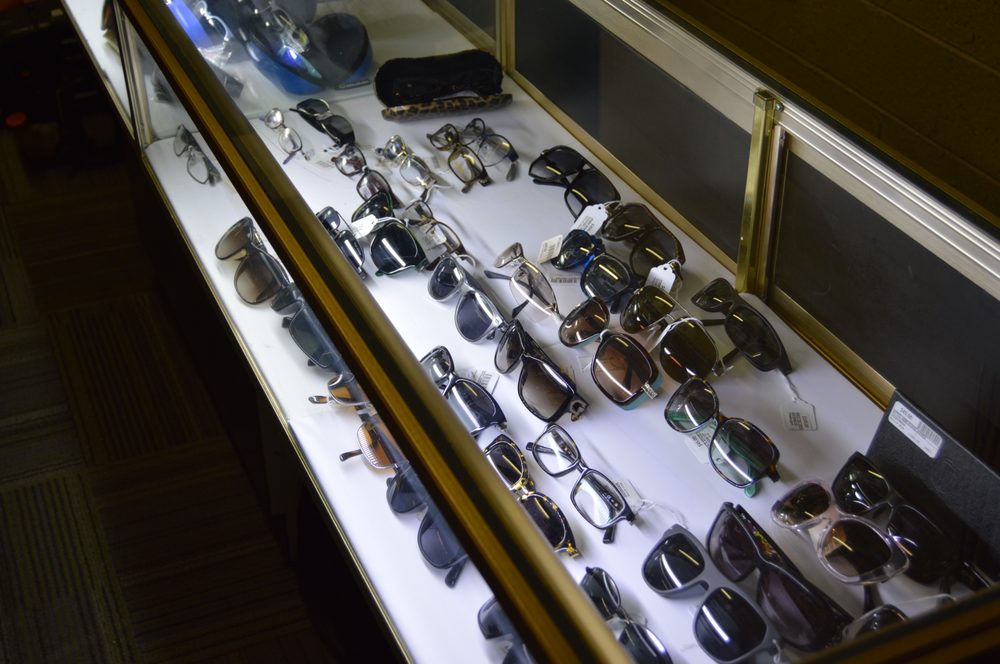 Display case filled with dozens of pairs of designer sunglasses and eyewear frames