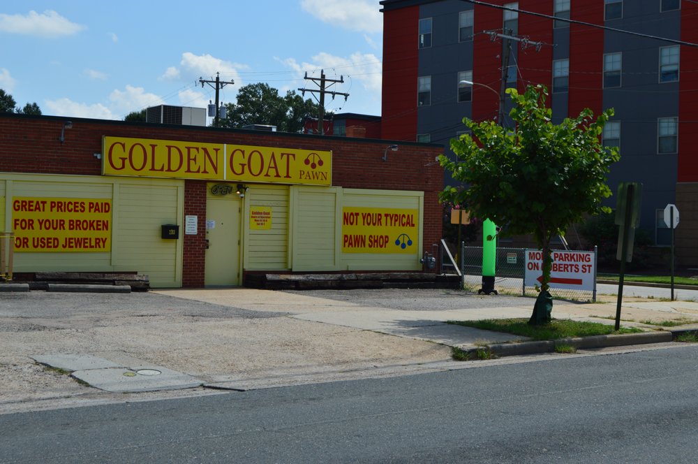 Golden Goat storefront exterior — a brick building with yellow ‘Not Your Typical Pawn Shop’ signage