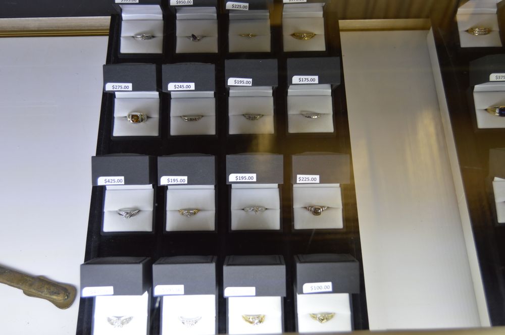 Rings with visible price tags arranged in a display case, showing transparent pricing
