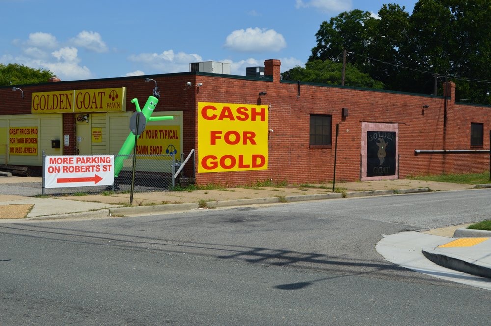 Side view of Golden Goat storefront featuring a large Cash for Gold sign