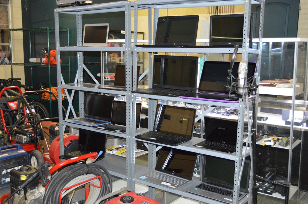 Metal shelving stocked with laptops, power tools, and consumer electronics