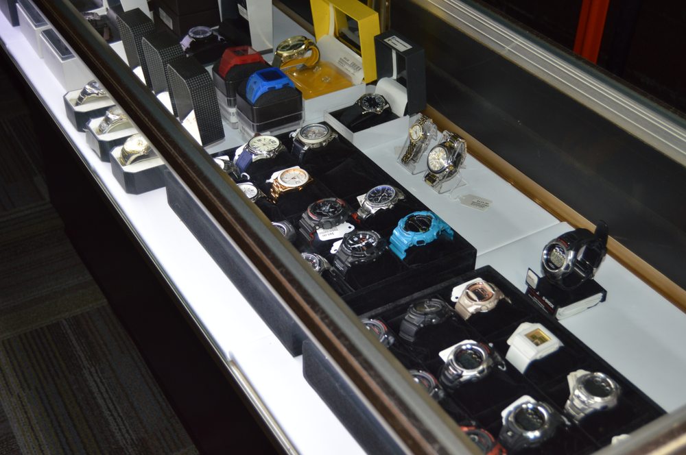 Row of sport and dive watches including G-Shock and Casio models in a lit display case